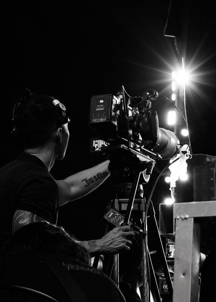 Cameraman operating professional equipment at a night event. Capturing dynamic moments in black and white.