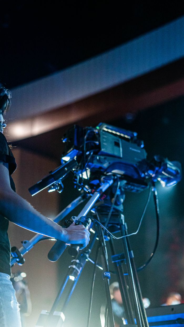 Crop person using professional camera to shoot video of music show during performance